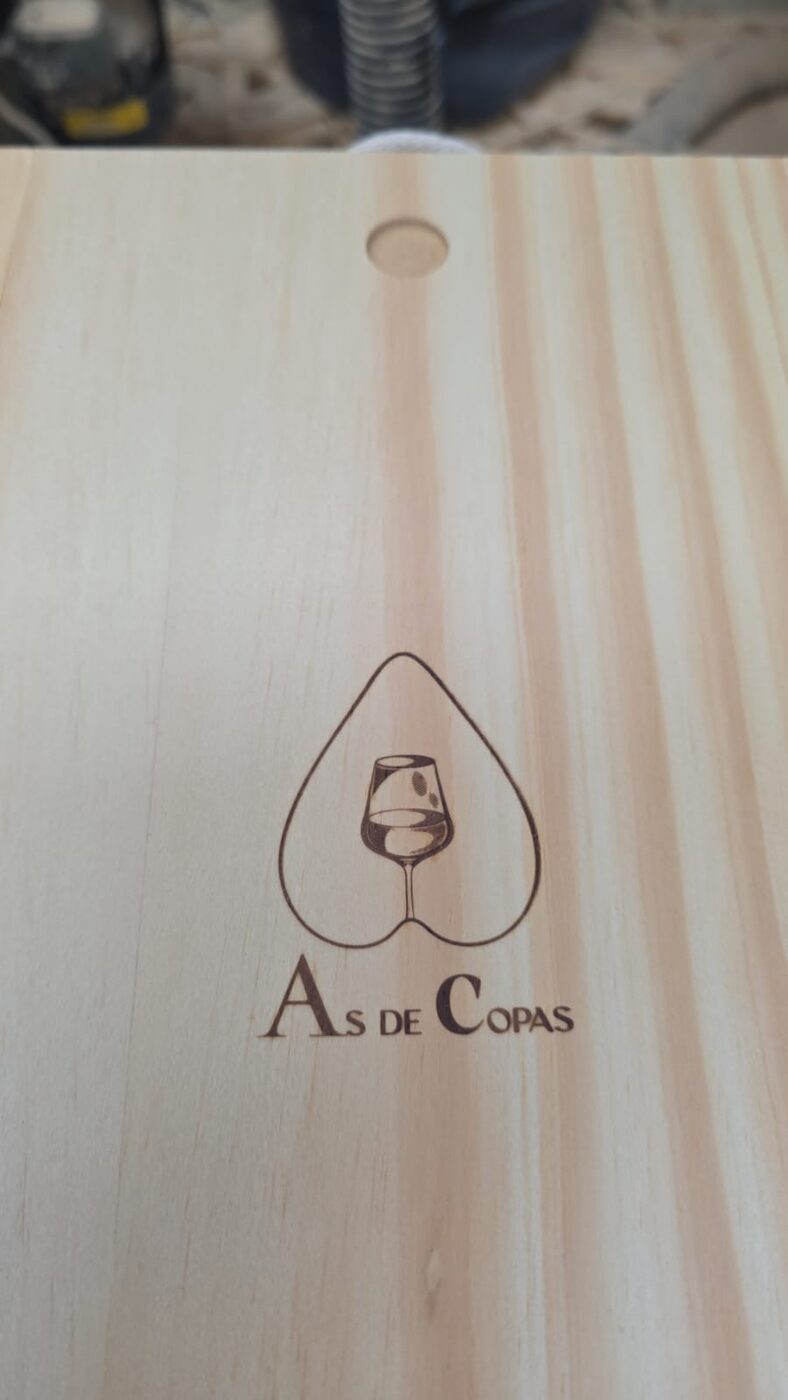 Tapa de caja de pino con el logo de As de Copas grabado a láser