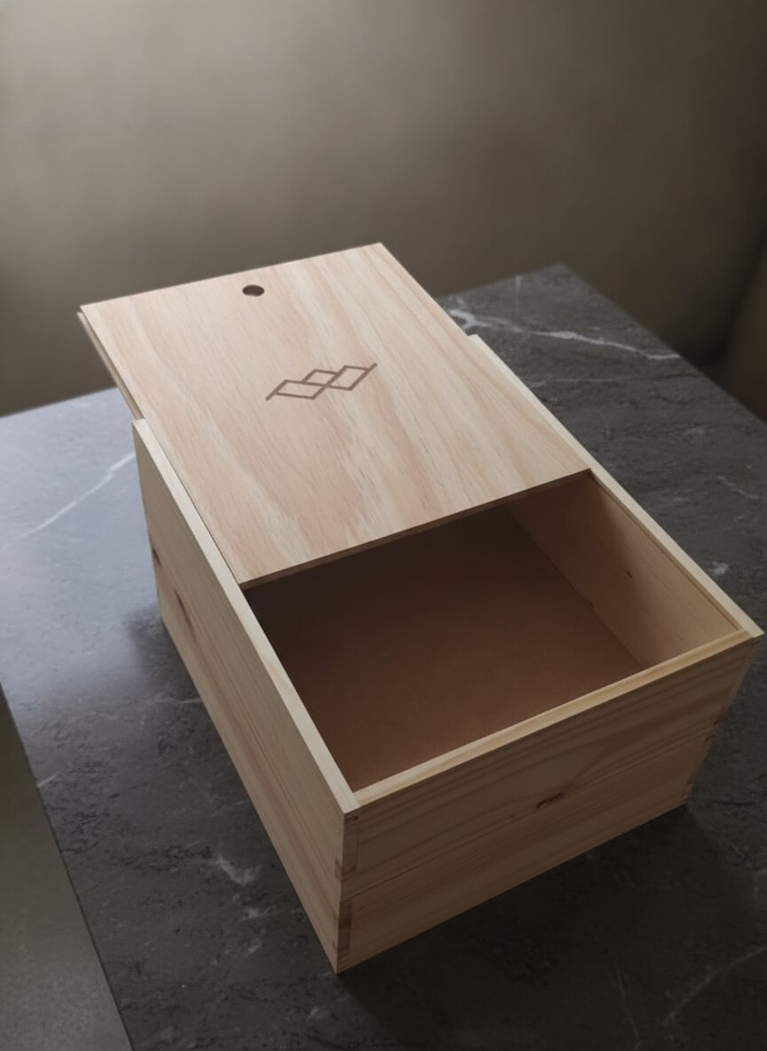 Caja vinera corporativa con grabado de rombos abierta mostrando el interior, sobre piedra oscura