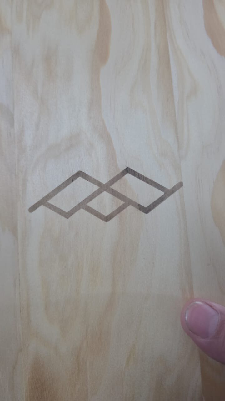 Mano sosteniendo una pieza de madera con el grabado láser de rombos en zigzag