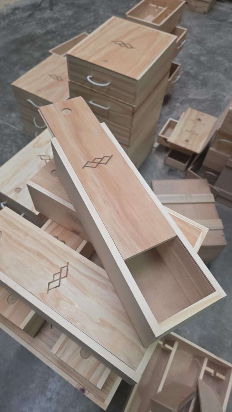 Decenas de cajas vineras corporativas apiladas en el taller